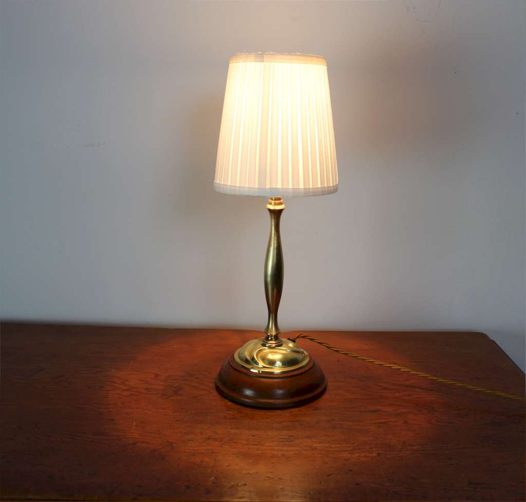 Arts and Crafts brass table lamp on wooden plinth.