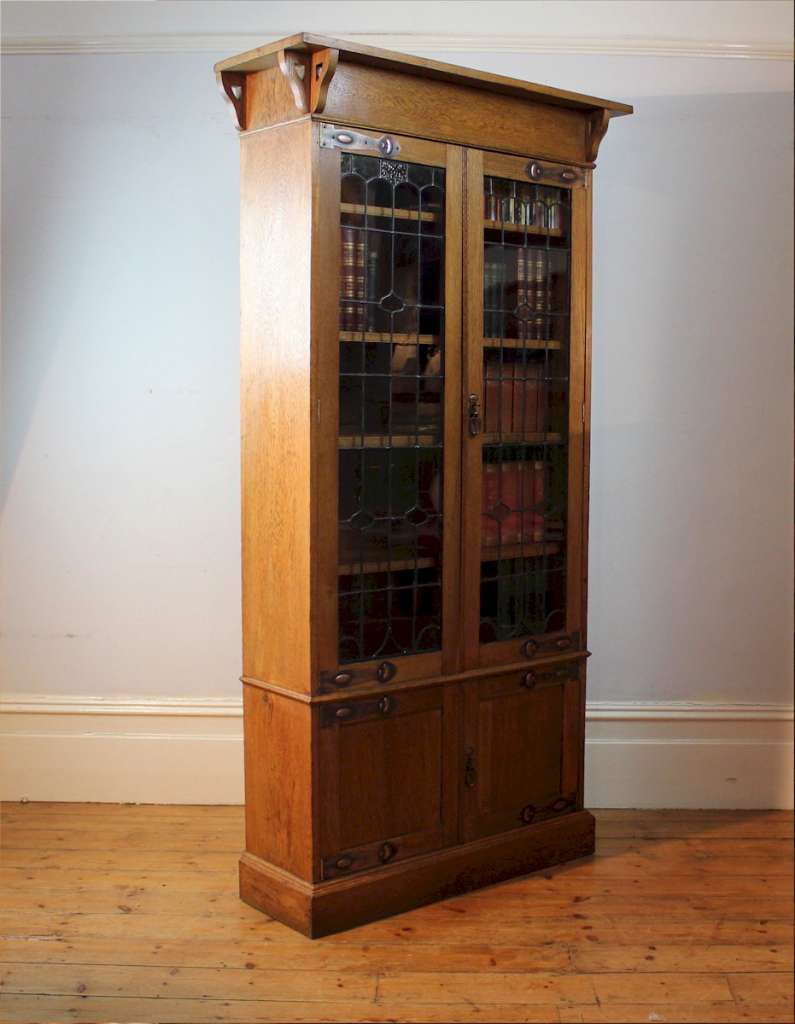 Arts and Crafts glazed bookcase in oak with coppered straps