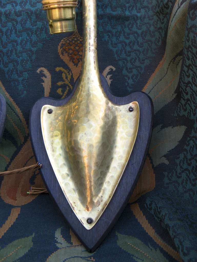 Pair of arts and crafts wall lights in hammered brass on wooden heart shaped backplates