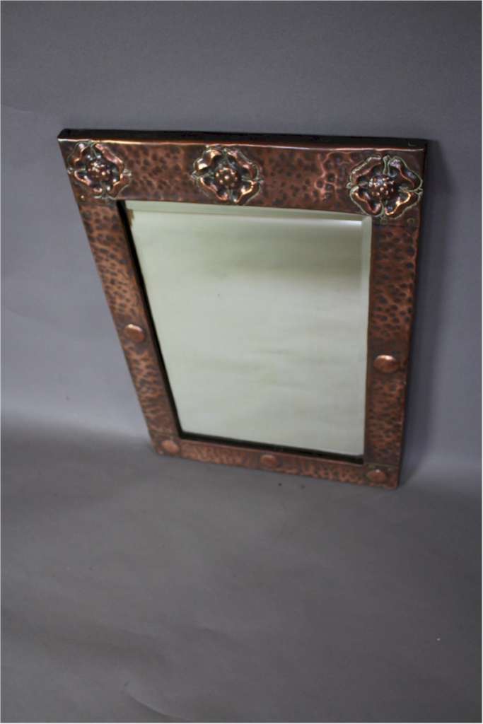 Arts and Crafts copper framed wall mirror with three stylised flower heads c1900