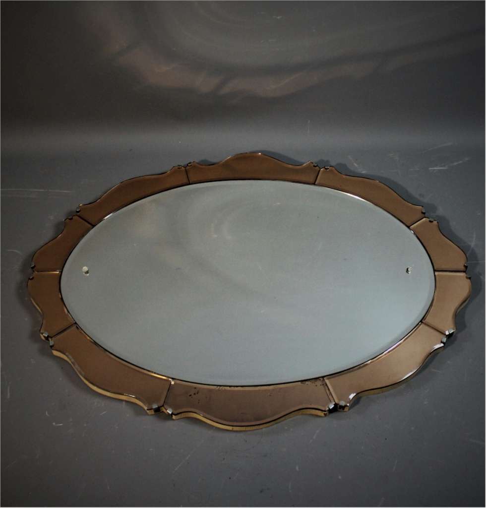 Art Deco oval mirror with peach scalloped border.