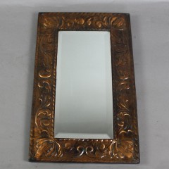 Copper arts and crafts mirror with scrolling leaf design.