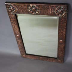 Arts and Crafts copper framed wall mirror with three stylised flower heads c1900